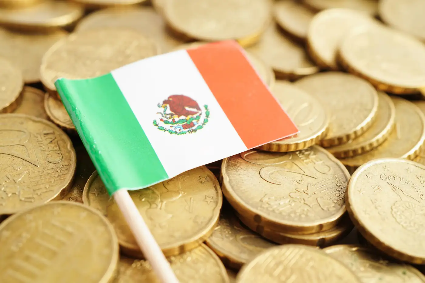 Bandera de México sobre monedas representando la economía de ese país