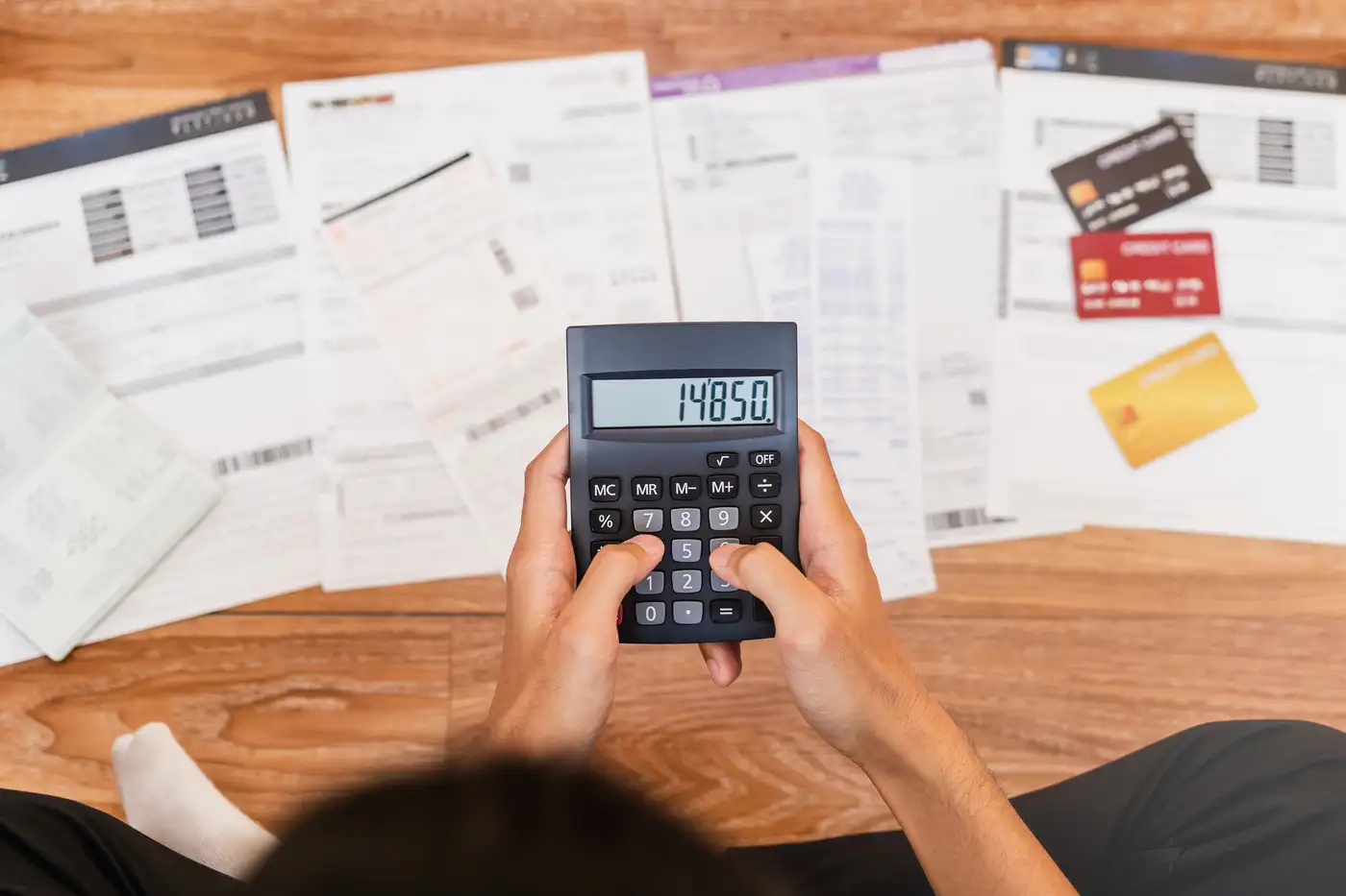 hombre con una calculadora y muchos estados de deuda que necesita consolidar