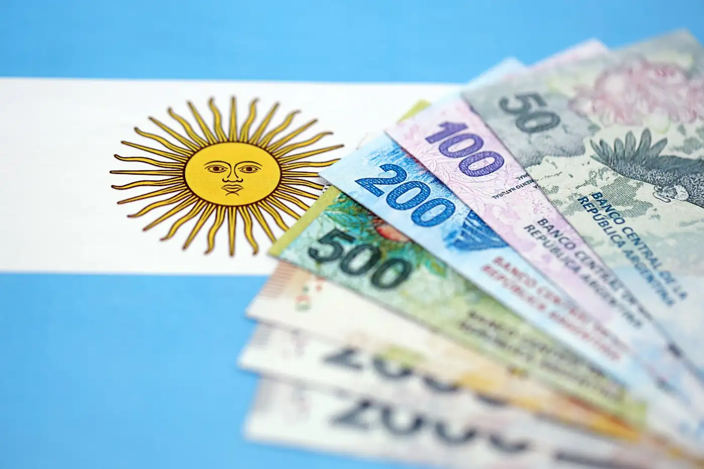 bandera Argentina en el fondo con billetes de ese país representando su economía
